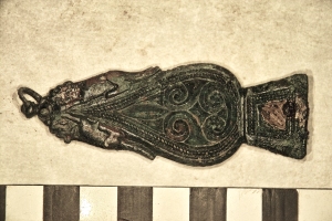 The strap end is decorated with crouching dogs on either side of its tapered end.